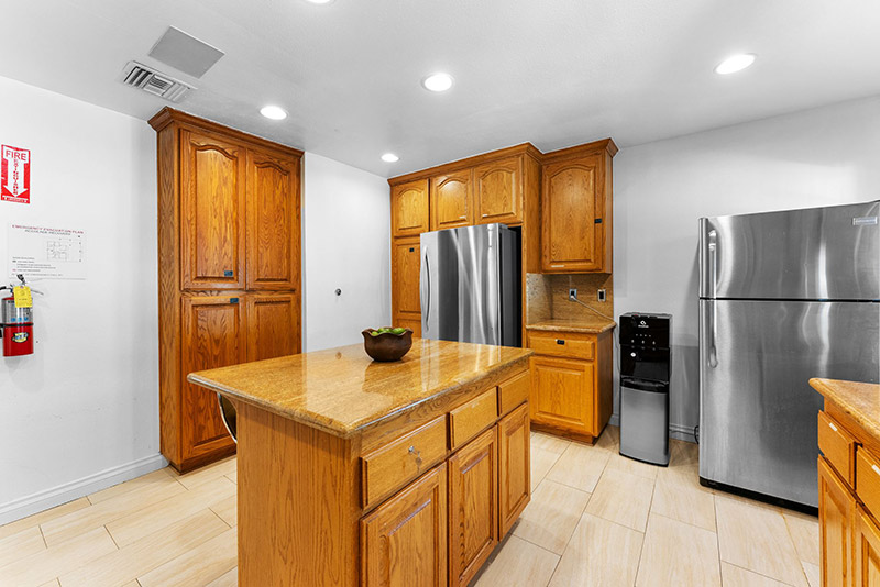 Kitchen with a granite island, stainless refrigerator, and built-in beverage station