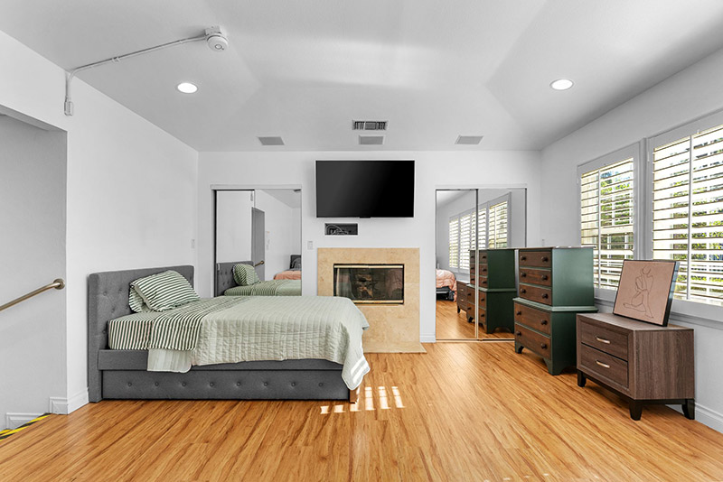 Bedroom with a fireplace, wall-mounted TV, and mirrored closet doors
