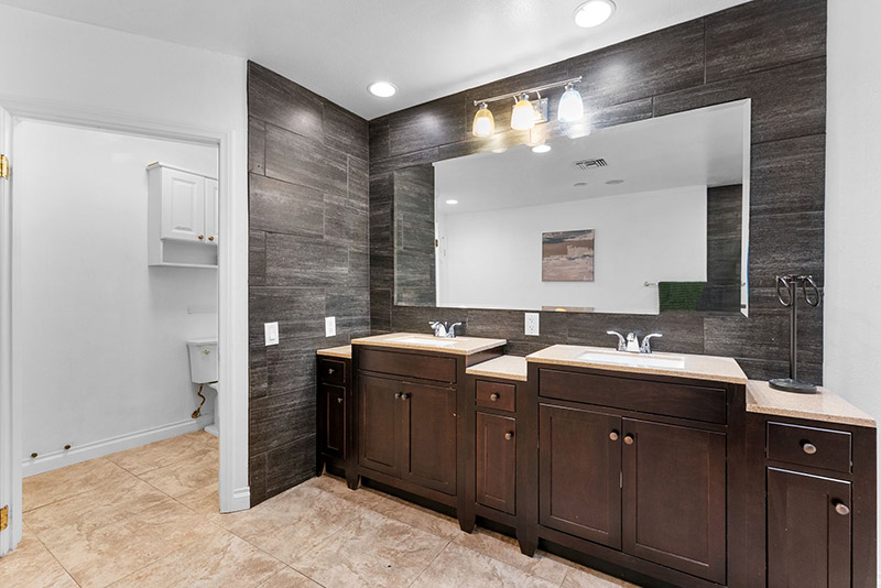 Bathroom with dual vanity sinks and a large lighted mirror