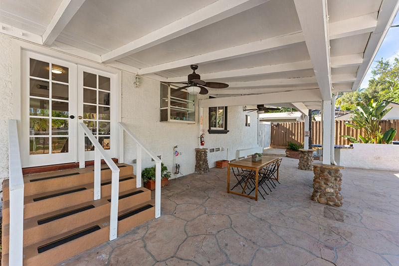 Covered back patio with an outdoor dining table and French doors leading inside