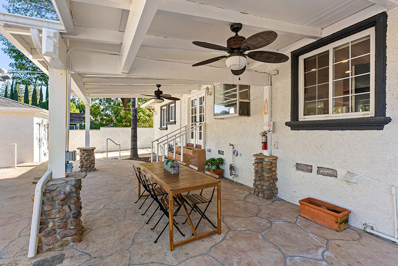 Covered patio along the side of the house with a wood dining table
