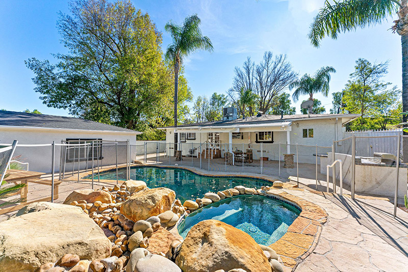 Pool and spa area with safety fencing and the main house in the background
