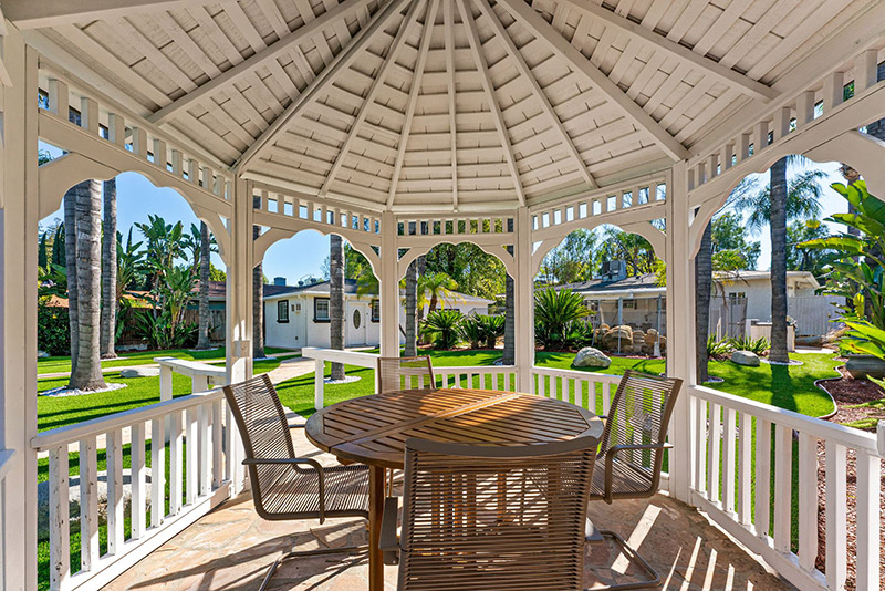 Interior of the gazebo with a round table, chairs, and garden views