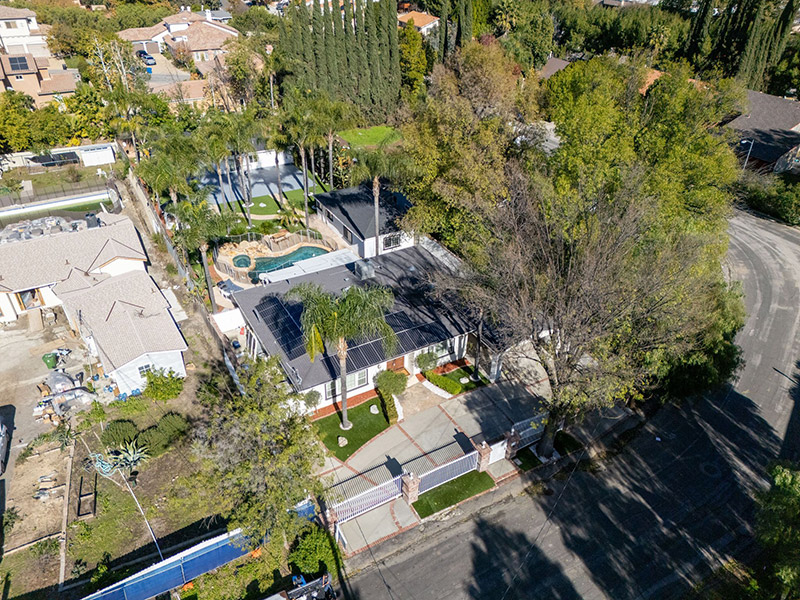 Aerial view of the property showing the pool, sport court, and gated driveway