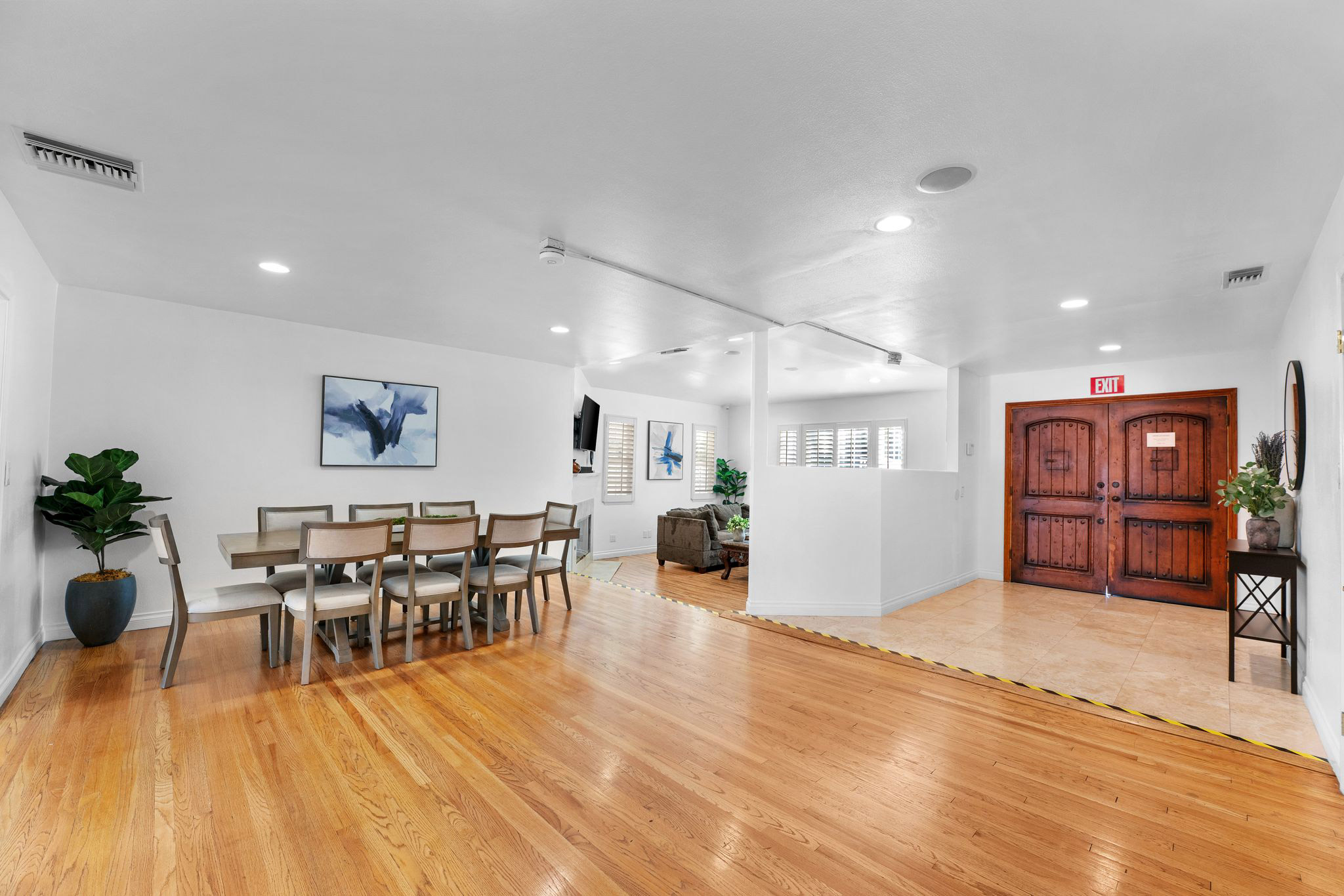 Open dining and living area with abstract artwork and large wood double doors marked Exit