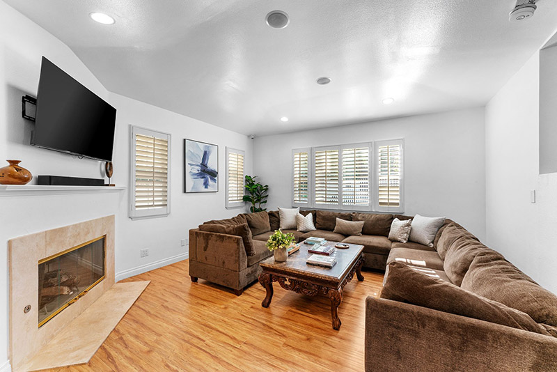 Living room with a sectional sofa, wall-mounted TV, and stone fireplace