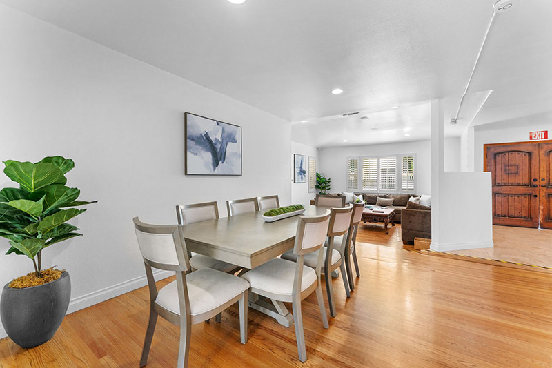 Dining table beside a fiddle-leaf fig plant, with a view into an adjoining living room